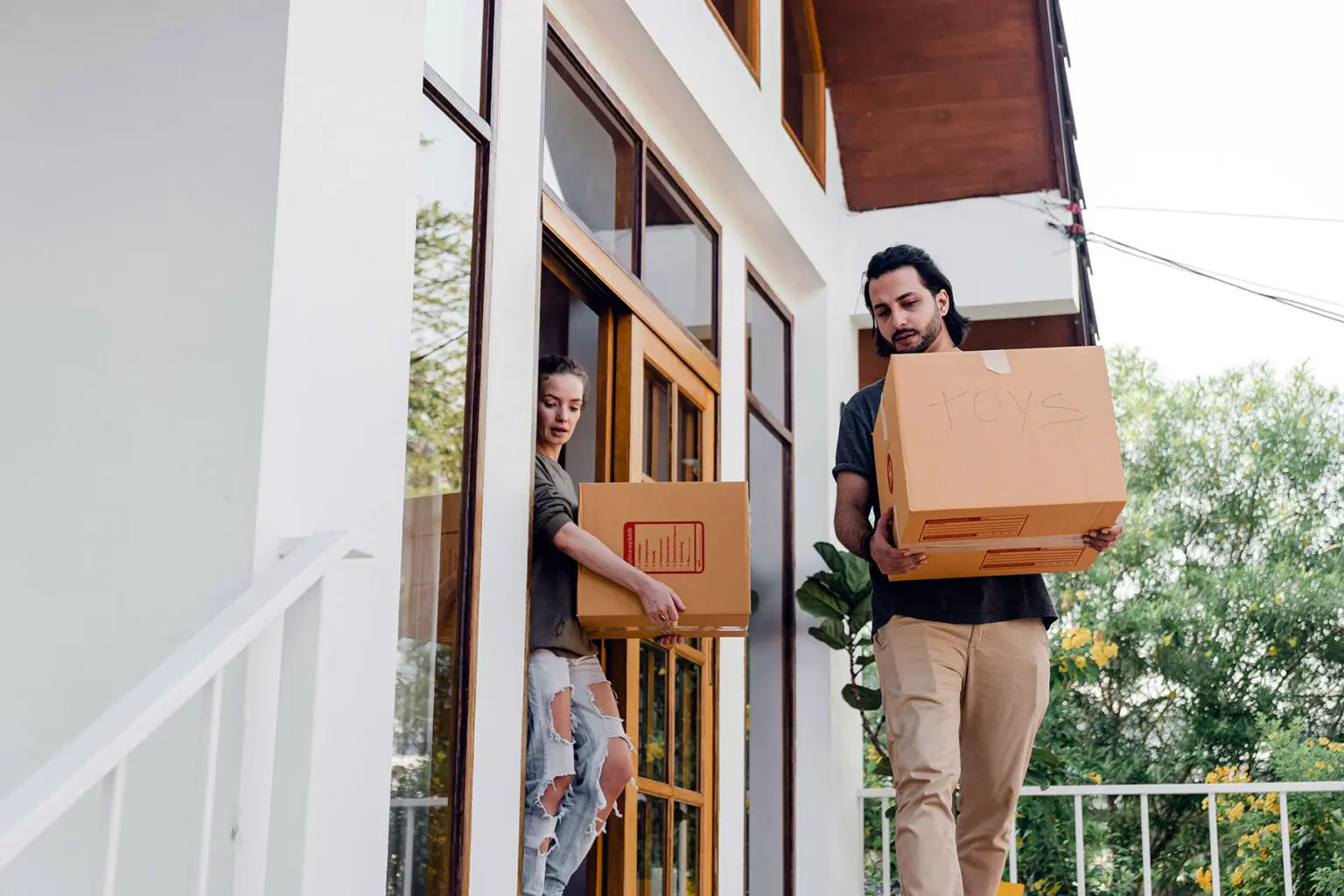 Couple carrying moving boxes out of their home.